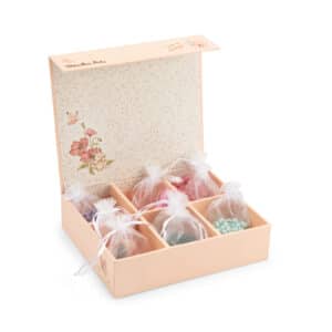 Geopende roze Moulin Roty kralendoos Les Rosalies met organzazakjes vol houten kralen